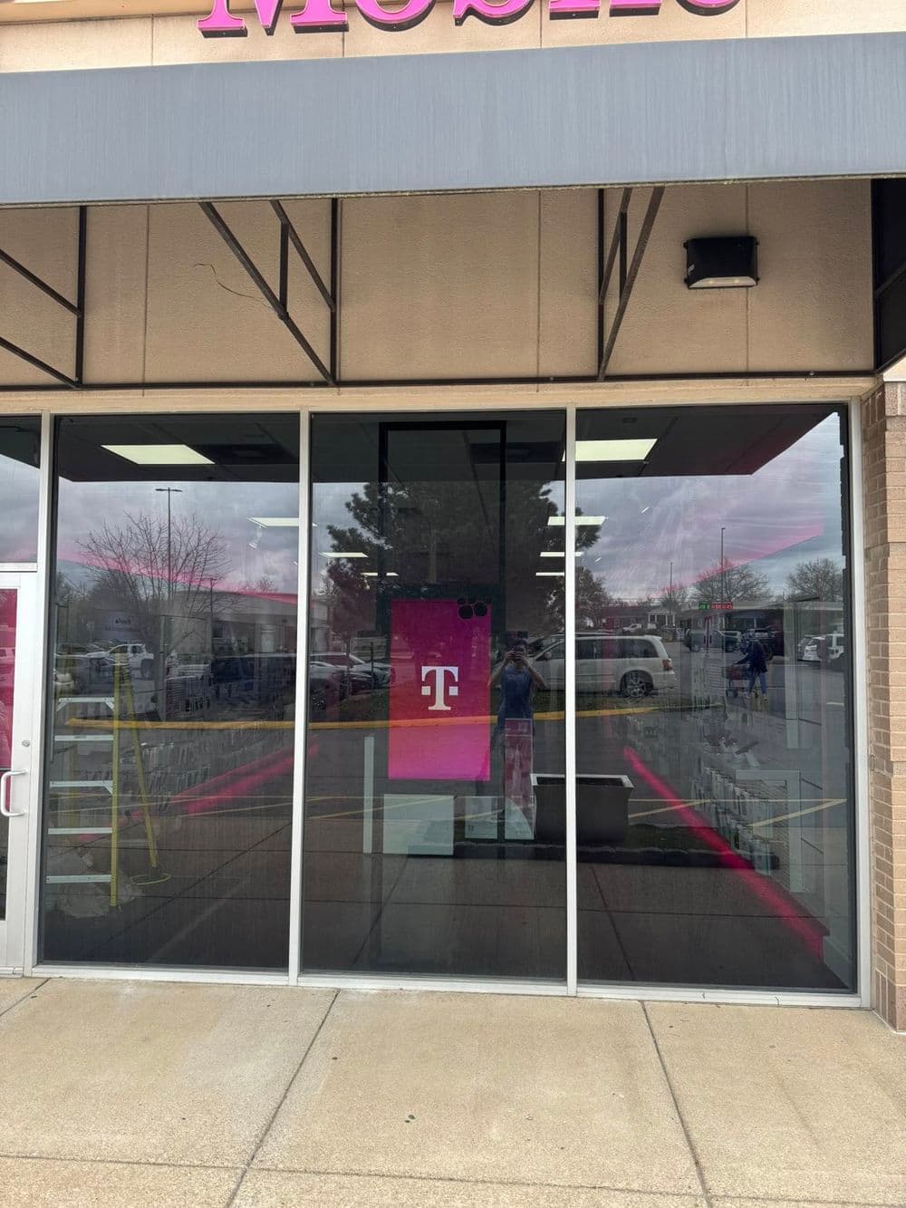 T-Mobile store entrance with large logo and reflective window, featuring a clean exterior.