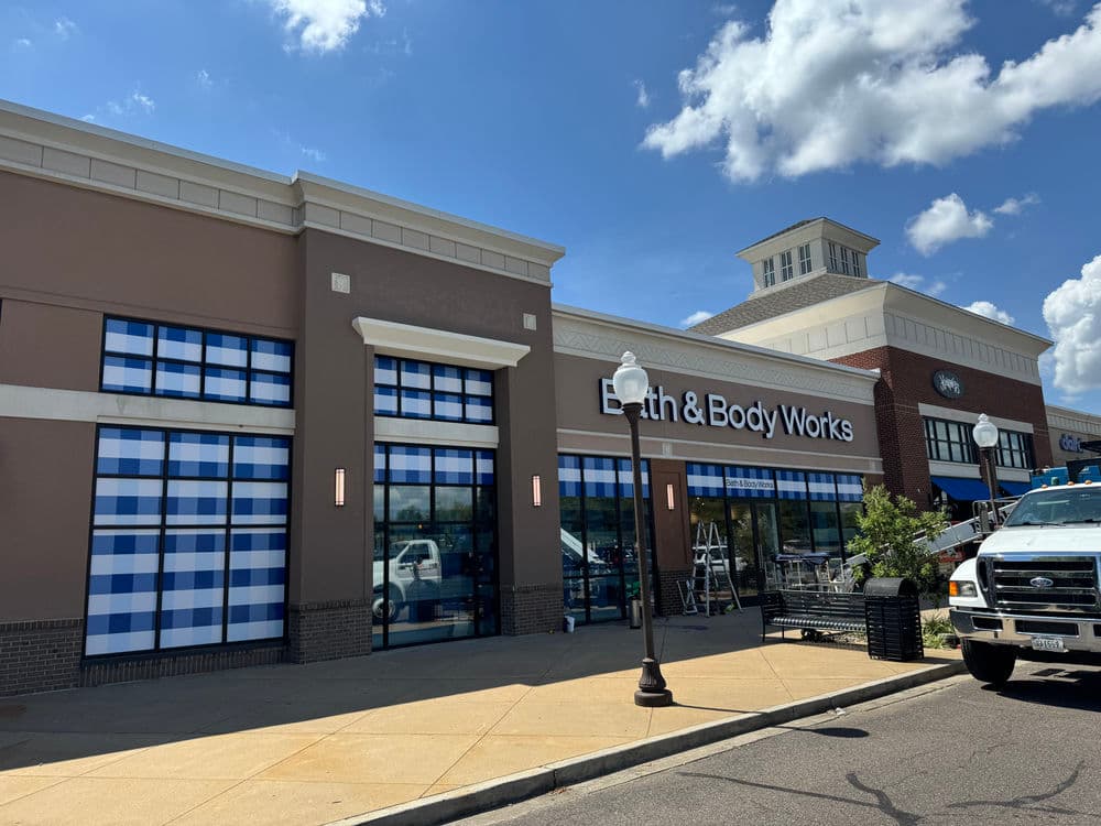 Bath & Body Works storefront with blue checkered window coverings on a sunny day.