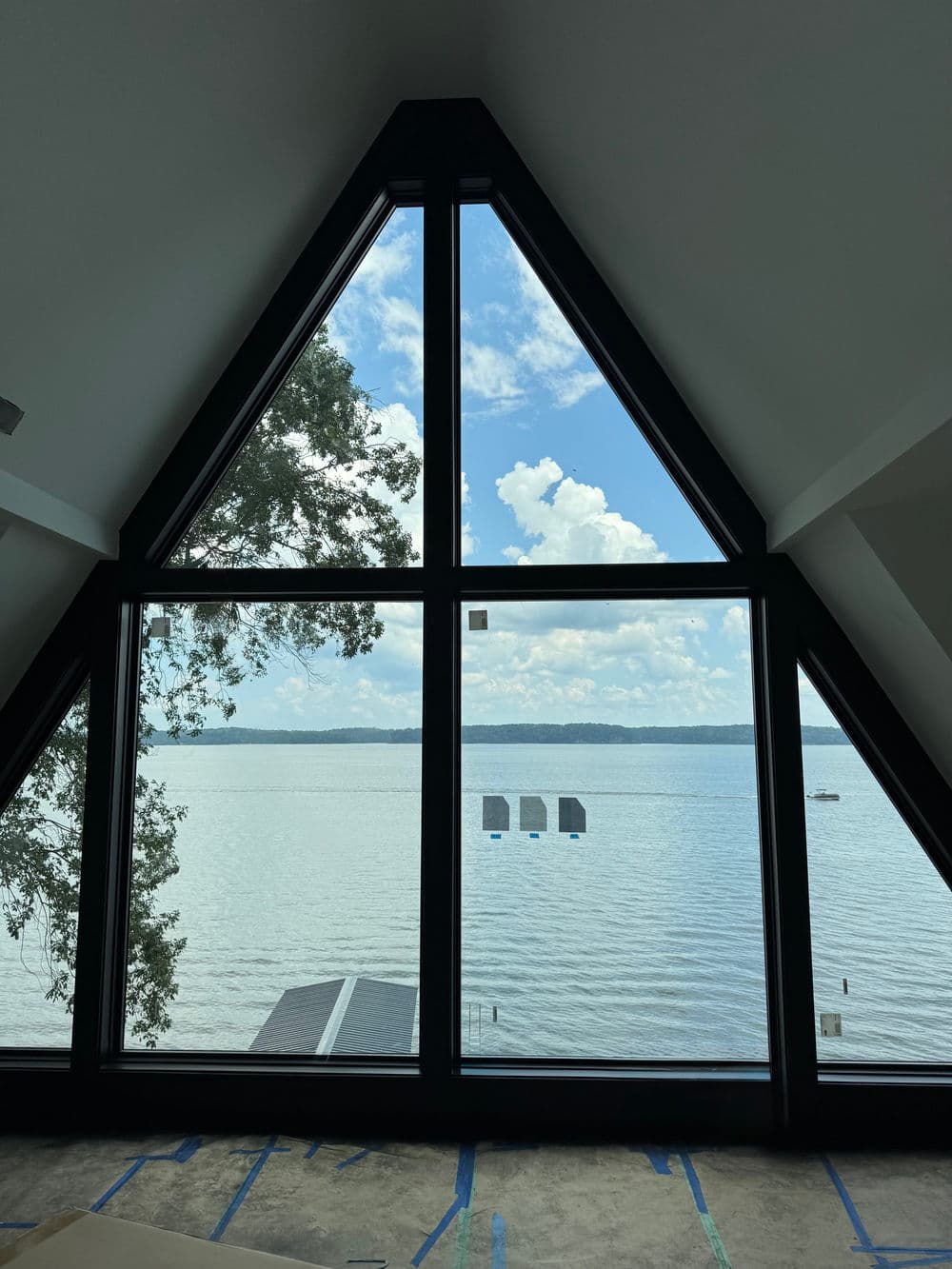 A-frame cabin view overlooking a serene lake with sailboats and blue sky.