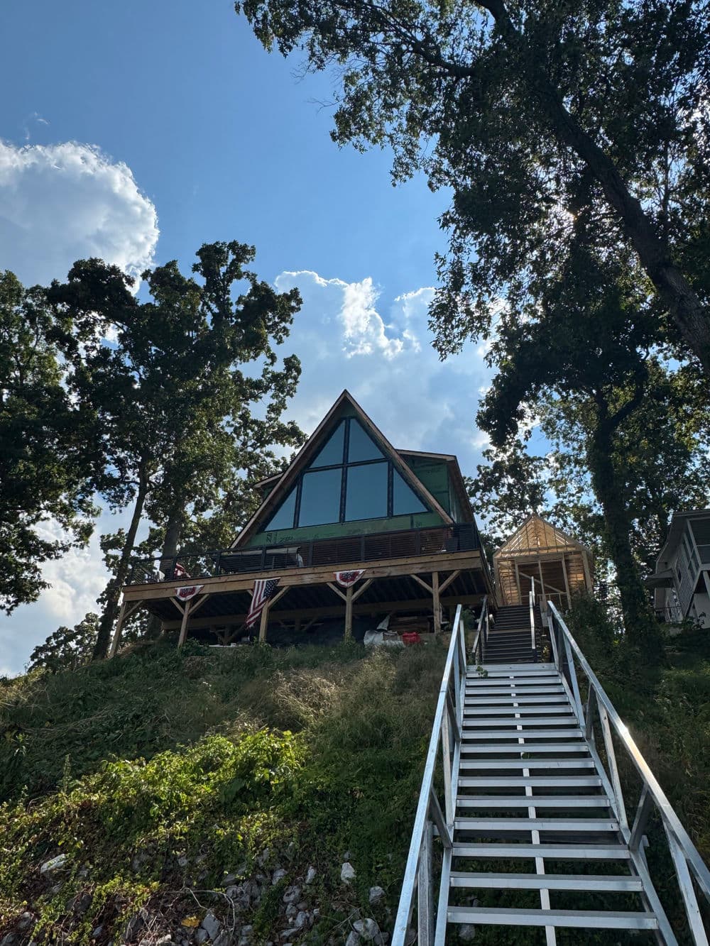 A-frame cabin nestled among trees with a staircase leading to the entrance.