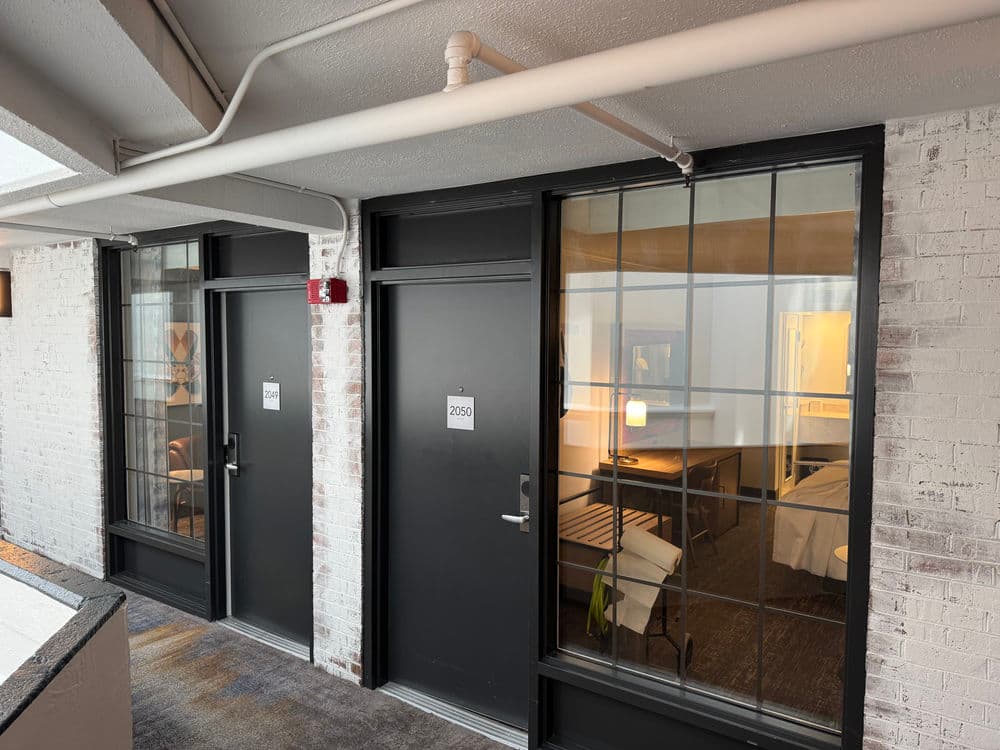 Hotel corridor showcasing two guestroom doors with modern design and ambient lighting.
