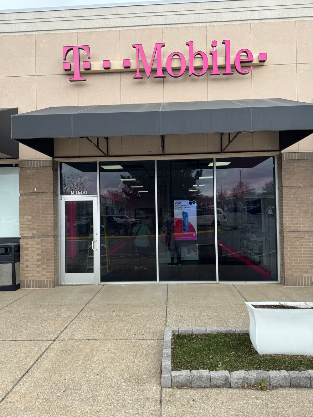T-Mobile store exterior with signage, glass doors, and promotional display in front.